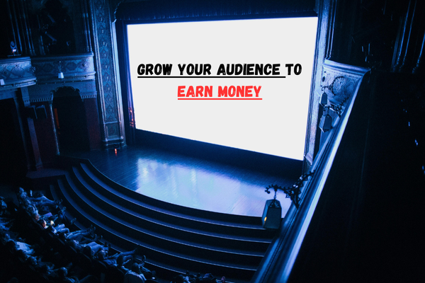 Large cinema screen displaying the words “Grow Your Audience to Earn Money” in bold black and red text, viewed by an audience inside a theater.