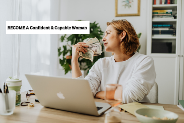 Smiling woman sitting at a desk with a laptop, holding cash and looking confident, symbolizing financial independence.