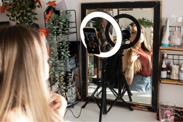 A woman recording a short video with a ring light and smartphone in front of a mirror, representing how housewives can earn money from home by creating micro YouTube channel content.
